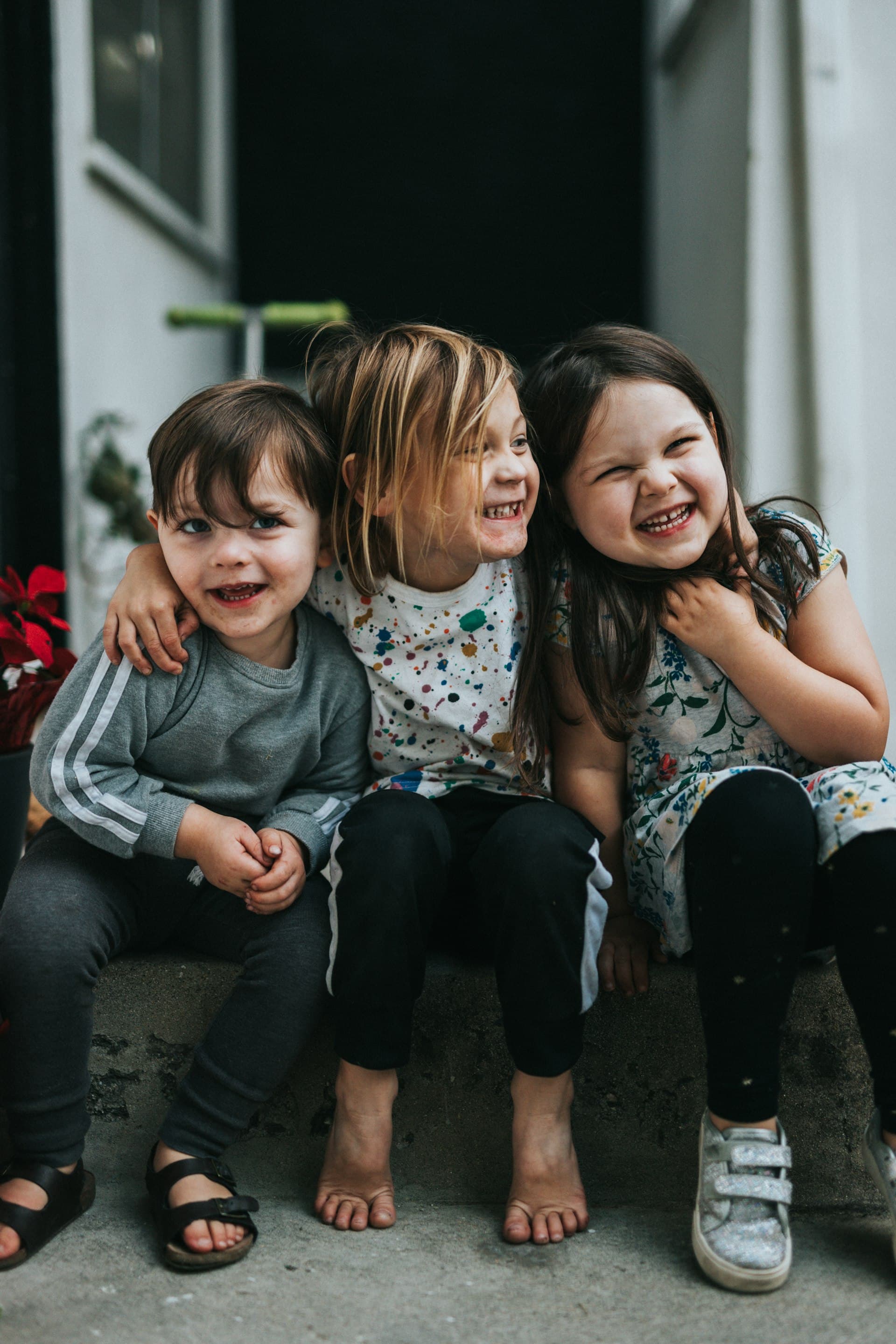 Three young children sitting together and laughing